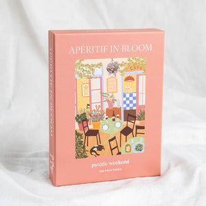 Puzzle box titled 'Apéritif in Bloom' with a colorful illustration of a patio scene on a white background.