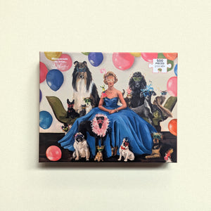 Colorful puzzle box with artwork of a seated woman in a fancy blue dress wearing a mask surrounded by balloons as well as dogs and cats also wearing masquerade masks