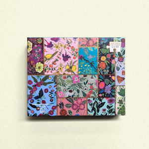 Top view look of a greenbox puzzle box featuring grid collage of illustrated wild flowers separated by gold foil zigzag on yellow background

