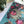 Close up of finished portion of puzzle showing three birds inside a birdhouse made of grasses atop a blue-green patterned background. Puzzle is atop a white surface next to some plants.