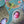 Partial view of completed puzzle with art of a green bird flying while a red and blue bird sit inside hanging bird houses made of grass. 