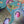 A close-up of a colorful jigsaw puzzle featuring birds in nests, with a green bird in flight and pink and gray birds in straw nests against a teal background.