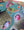 A close-up of a colorful jigsaw puzzle featuring birds in nests, with a green bird in flight and pink and gray birds in straw nests against a teal background.