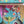 A completed jigsaw puzzle showing a colorful nature scene with birds, butterflies, and nests on a turquoise background, with part of the matching puzzle box visible at the top.