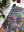 Colorful leaf-patterned fabric on a white surface with a plant in the background