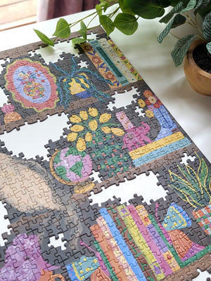 Jigsaw puzzle with colorful artwork on a white surface with a plant in the background