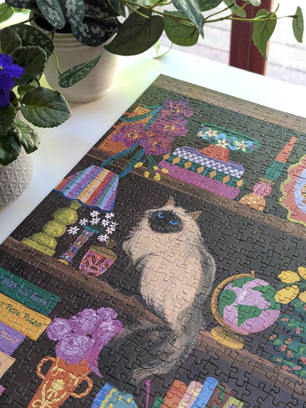Jigsaw puzzle with a cat design on a table with plants in the background