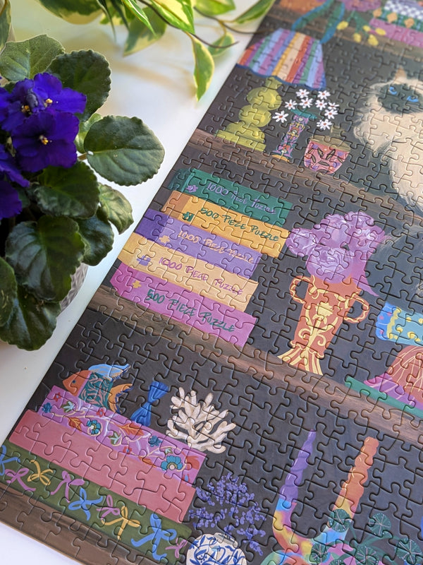 Colorful puzzle with a decorated bookcase design on a white surface next to a potted plant.