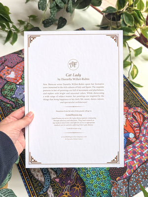 Hand holding a document titled 'Cat Lady' by Daniella Wilken Rabin, with a colorful cat-themed puzzle in the background.
