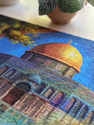 Close up of top-center portion of completed puzzle showing a beautiful golden dome near a potted plant on white.
