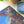 Close up of corner of the completed Golden Domes puzzle showing vibrant archway and flying pigeons. Next to plant and top of tube packaging.