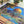 Jigsaw puzzle with a completed section featuring a colorful architectural scene, surrounded by potted plants.