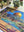 Jigsaw puzzle with a completed section featuring a colorful architectural scene, surrounded by potted plants.
