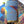 Hand holding a puzzle packaged in a tube style container in front of a completed version of the puzzle blurred in the background