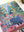 A completed jigsaw puzzle featuring a colorful tropical scene with a woman, cats, birds, and lush green foliage, photographed on a light surface.