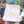 A small off-white fabric drawstring pouch with the words 'puzzle weekend' printed in yellow lowercase letters, placed on top of a colorful jigsaw puzzle.
