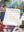 A small off-white fabric drawstring pouch with the words 'puzzle weekend' printed in yellow lowercase letters, placed on top of a colorful jigsaw puzzle.