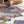 An out of focus person sits behind a white desktop upon which a partially completed mountain scene puzzle sits.