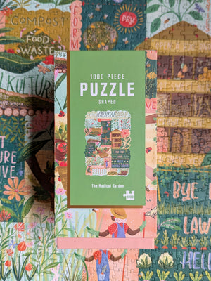 A 1000-piece puzzle box labeled 'The Radical Garden' lies upon a completed partial view of the puzzle.