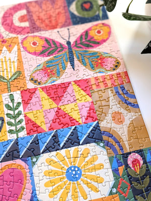 Partial view of a completed jigsaw puzzle with colorful patchwork of patterns, flowers, and butterflies. 