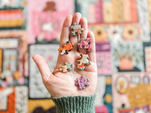 Hand holding colorful puzzle pieces with a blurred multicolored background of the completed puzzle.