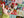 A hand holds several small, colorful Christmas-themed jigsaw puzzle pieces in front of a festive quilted background with Santa and holiday motifs.