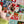 A hand holds several small, colorful Christmas-themed jigsaw puzzle pieces in front of a festive quilted background with Santa and holiday motifs.