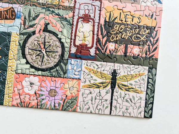 Close up of colorful puzzle section with various designs including a compass, dragonfly, flowers, and text on a white background