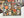 An art print featuring a colorful Halloween design with sugar skulls, jack-o'-lanterns, candelabras, and butterflies on a black background, displayed on a white surface with a partial view of a completed puzzle featuring the same art.
