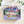 Top view of puzzle box showing illustration of beautiful mountain and valley scene. Box is on white background surrounded by small foliage.
