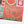 A close-up of a completed jigsaw puzzle featuring a fall harvest design with the words 'farm fresh PUMPKINS' in dark green script on a coral background, surrounded by floral and pumpkin illustrations in red, pink, teal, and gold.