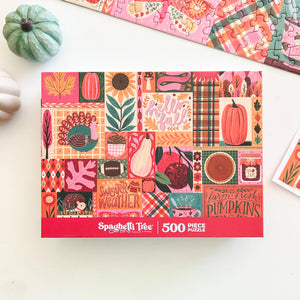 A 500-piece Fall-themed jigsaw puzzle box by Spaghetti Tree displayed on a white surface with decorative pumpkins and a partial puzzle piece arrangement in the background.