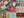A 1000-piece jigsaw puzzle box labeled 'Spaghetti Tide' is placed diagonally over the completed patchwork-style Christmas jigsaw puzzle featuring festive designs like Santa, snowflakes, trees, houses, and red trucks.