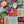 A 1000-piece jigsaw puzzle box labeled 'Spaghetti Tide' is placed diagonally over the completed patchwork-style Christmas jigsaw puzzle featuring festive designs like Santa, snowflakes, trees, houses, and red trucks.