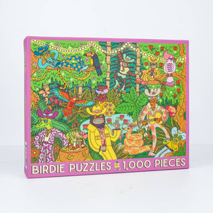 Photo of an angled jigsaw puzzle box against a white surface/wall. Box shows an illustration of a busy jungle scene with animals dressed up in funky human outfits playing guitars and holding a party. 