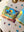 Jigsaw puzzle poster next to tube packaging surrounded by scattered puzzle pieces on top of tan fabric.