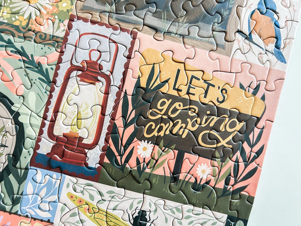 Close up image of a section of a jigsaw puzzle with 'Let's go camping' theme featuring a lantern and nature elements.