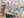 Puzzle box with colorful design featuring books and a cat, set against a a out of focus version of the completed puzzle in the background.