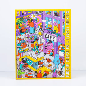 Photo of a jigsaw puzzle box against a white surface/wall. Box shows an illustration of a busy urban scene with many people and figures, including animal people going about their lives. 