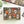 A 500-piece jigsaw puzzle box by Spaghetti Tree, featuring a colorful Day of the Dead/Halloween design with skulls, pumpkins, snakes, and candles on a black background. The box is displayed on a white desk with a plant and other puzzle pieces nearby.