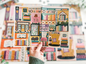 Hand holding a poster of the One More Chapter puzzle with illustrations of a cozy book-themed puzzle and text.