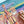 A close-up of a colorful jigsaw puzzle showing an abstract landscape or canyon scene, with a hand holding a small pink puzzle piece over the blank white gap in the puzzle.