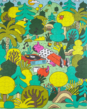 Close up photo of a completed jigsaw puzzle showing illustration of a man lying in the middle of a bunch of trees listening to music on a record player.